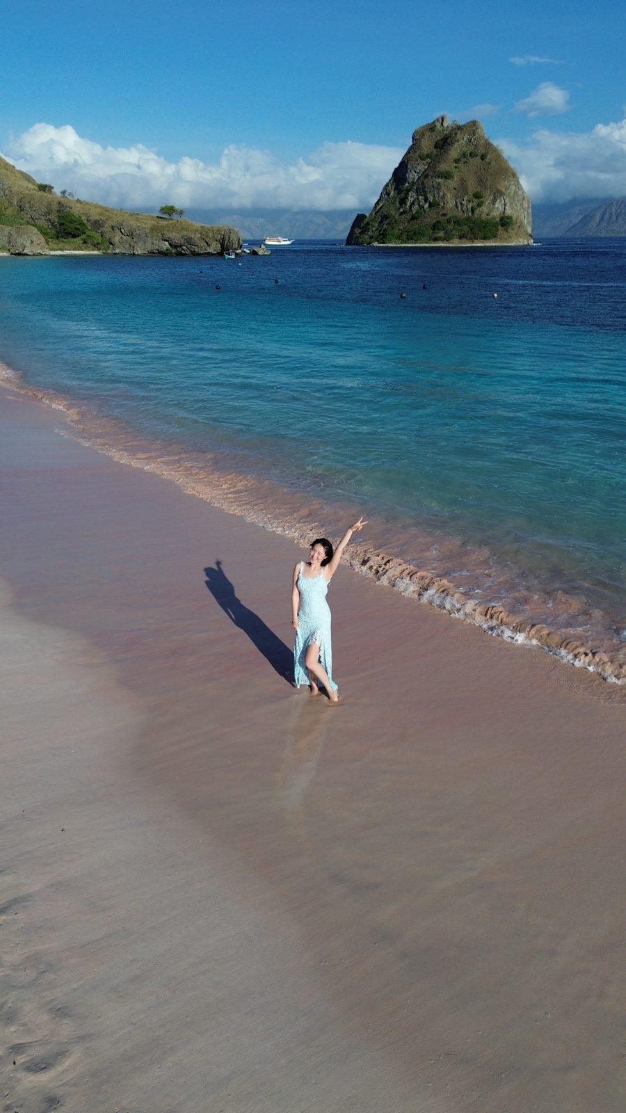 Swim Snorkel – woman in white at shore, rock islet behind (Real photo from a KEXI trip)